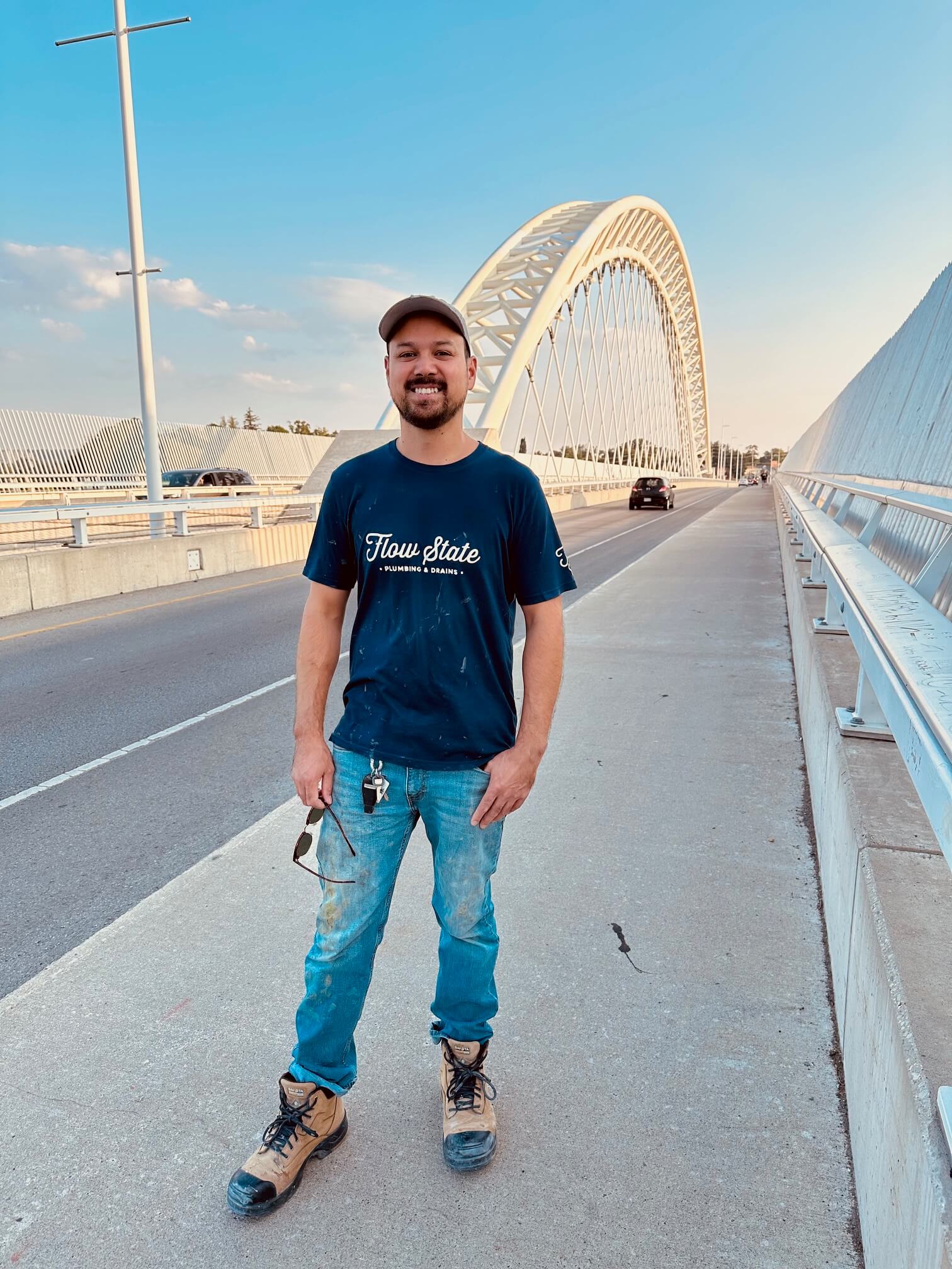 A smiling Niagara region plumber standing in front of the Burgoyne Bridge St. Catharines.
