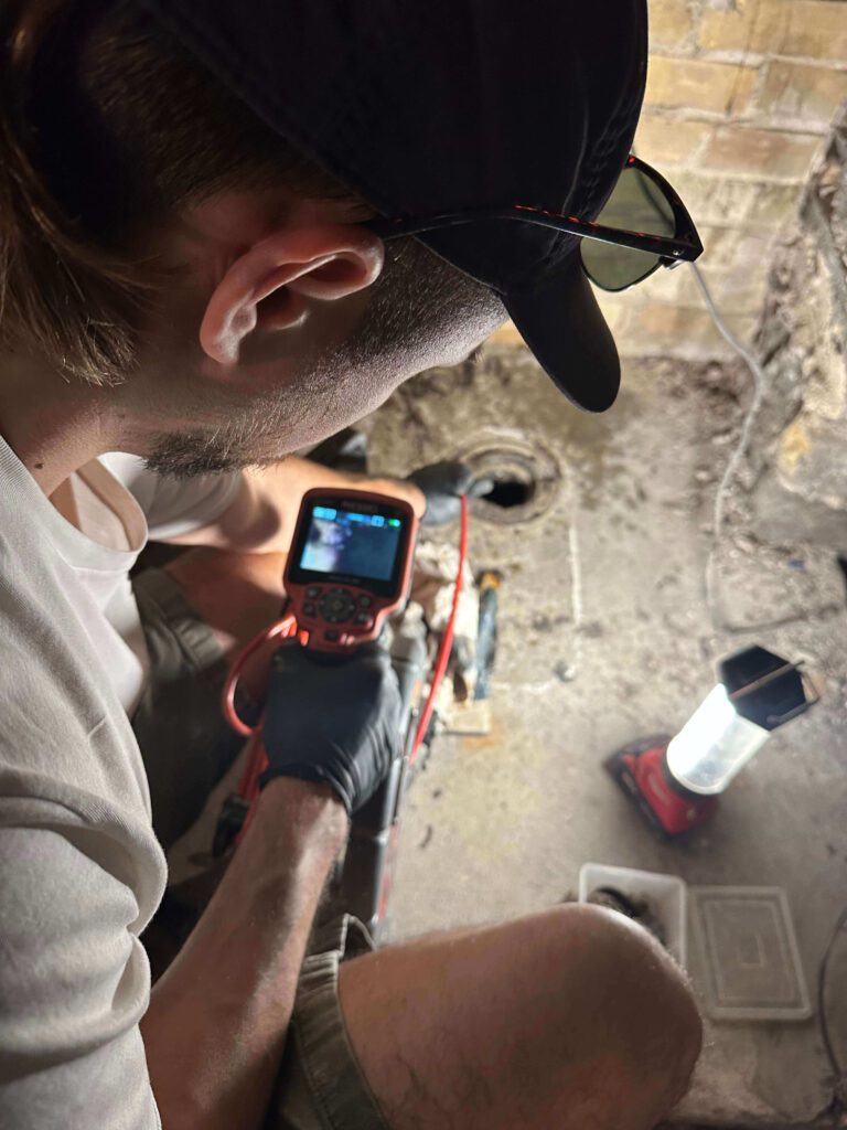 A Niagara Region plumber inspecting the insides of a clients drain with a drain inspection camera device.