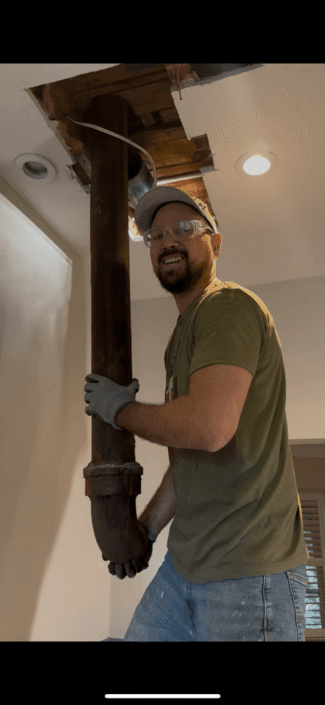 A licensed plumber from St. Catharines holding a cracked cast iron drain pipe at a clients century home.