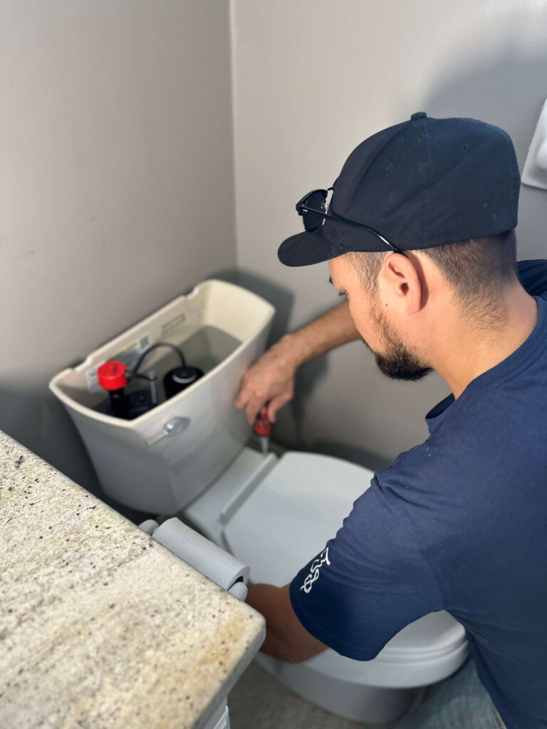 A plumber repairing a toilet at a clients home in Niagara Falls.