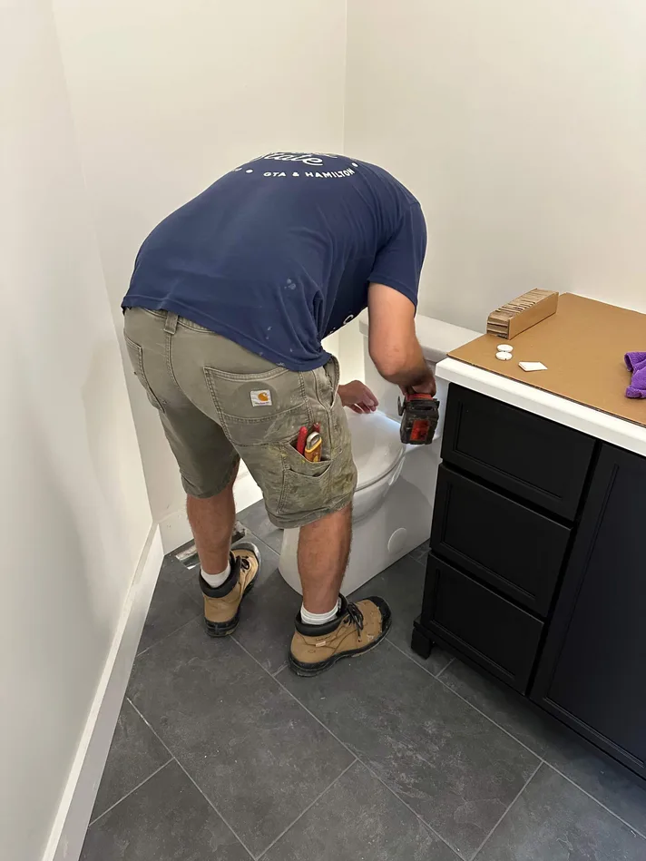 A flow-state plumber repairing a toilet tank in a St. Catharines home.