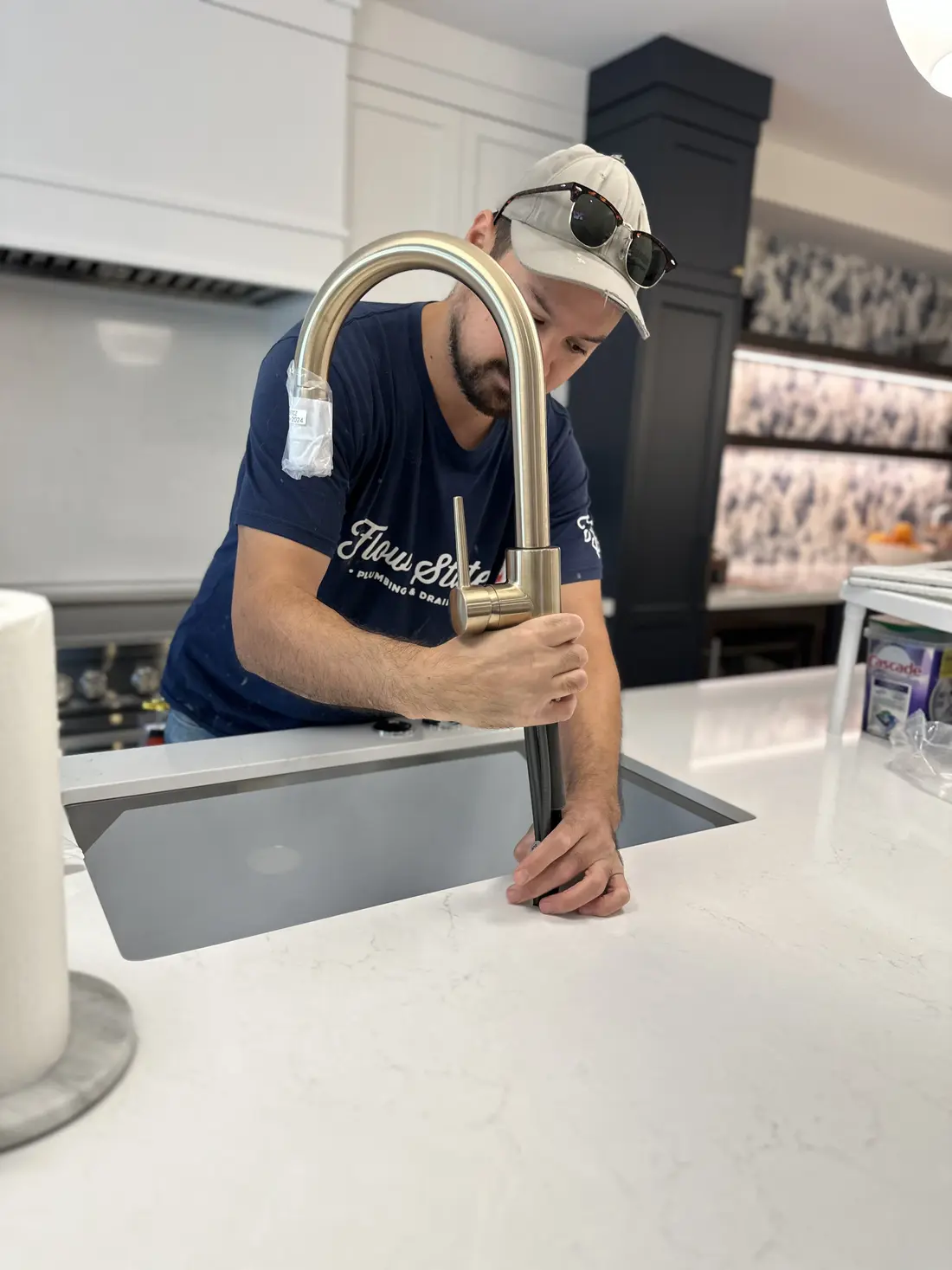 A plumber installing a kitchen faucet in a customers Niagara Falls kitchen.