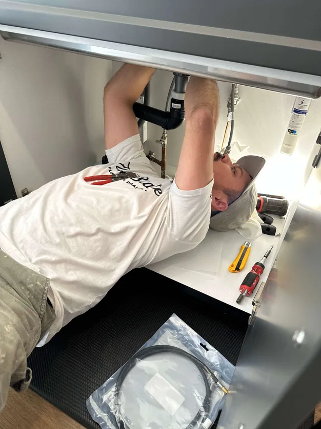 A plumber under a sink installing a customers faucet